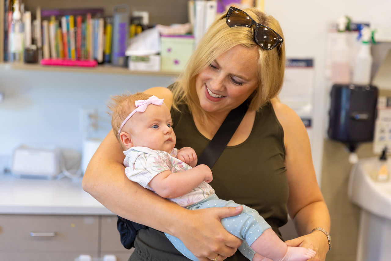 A mother holding and looking lovingly at her infant in a preschool classroom