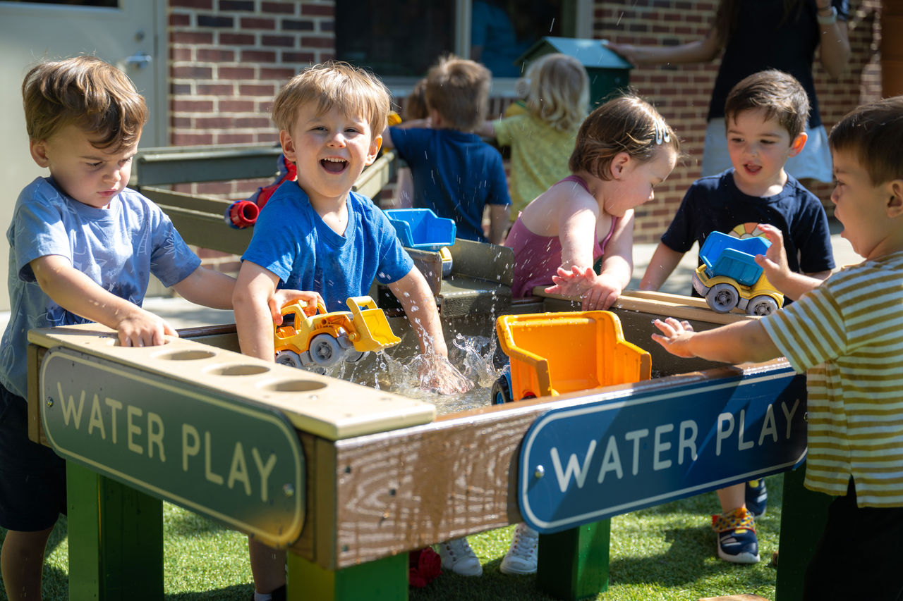 Children playing at a water table outside on a preschool playground