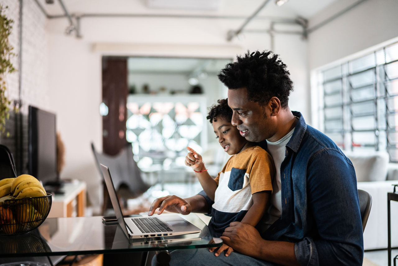 Father and son sit together at a computer reading a story