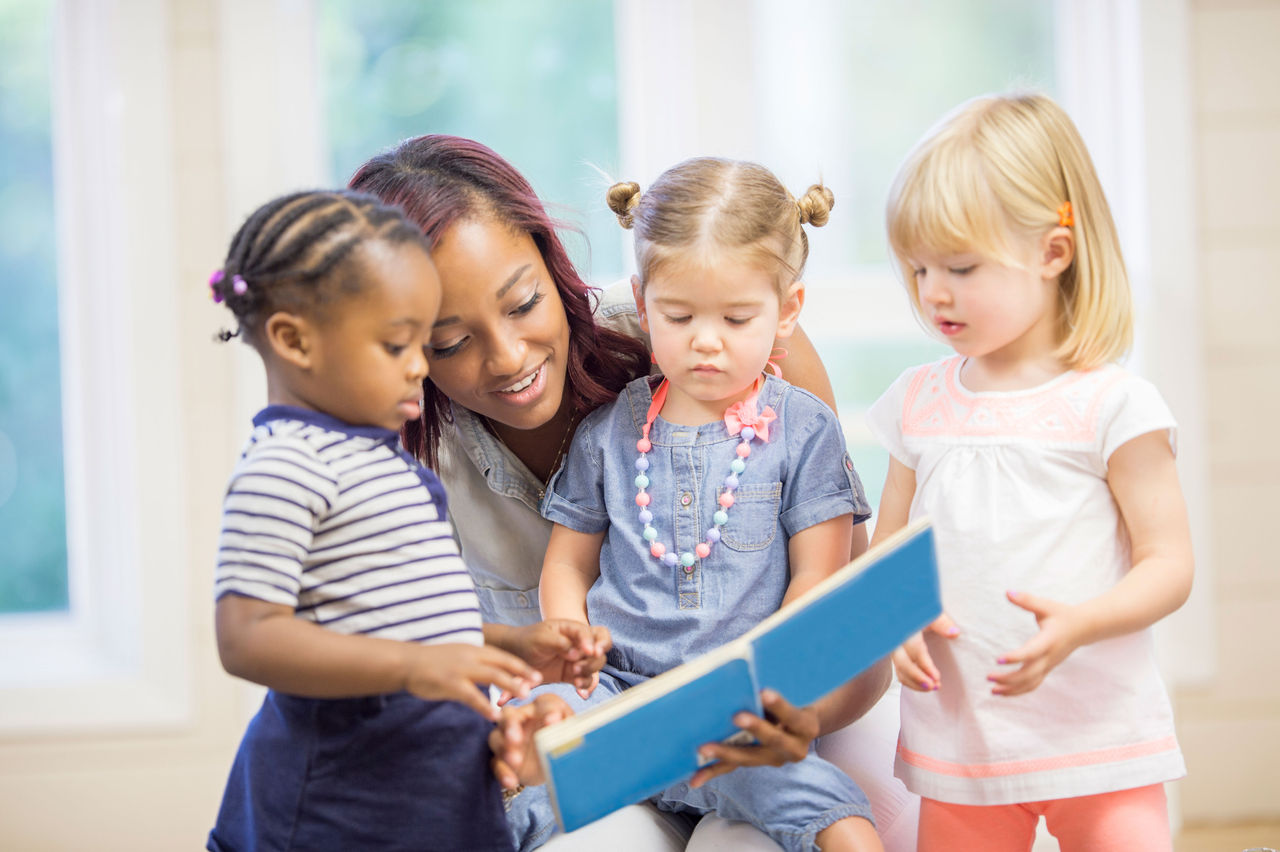 Teacher reading a story to two preschool children