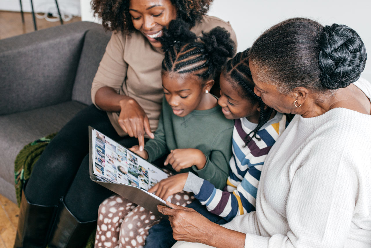 A multi-generational family of women sitting on the couch together looking at photos