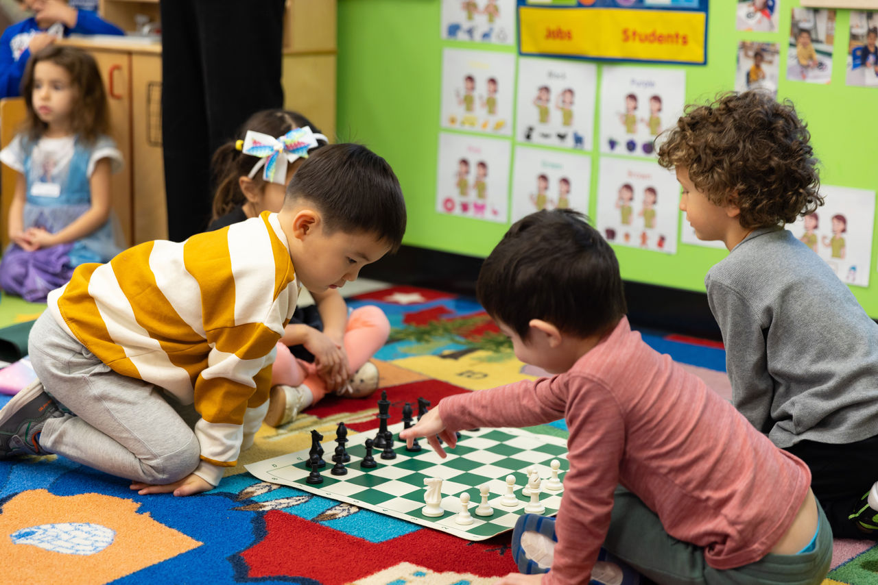 Children playing chess on the floor of a classroom