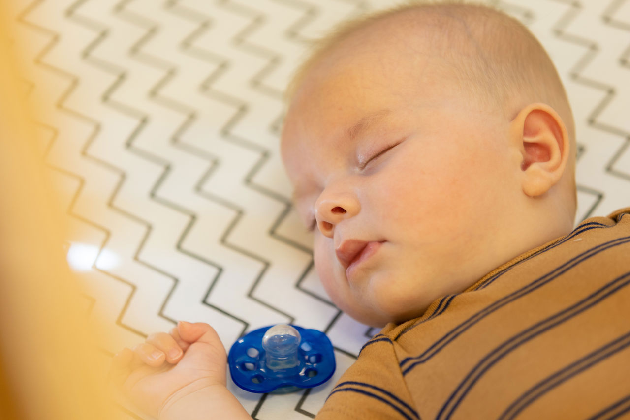 Infant sleeping safely on his back in a crib