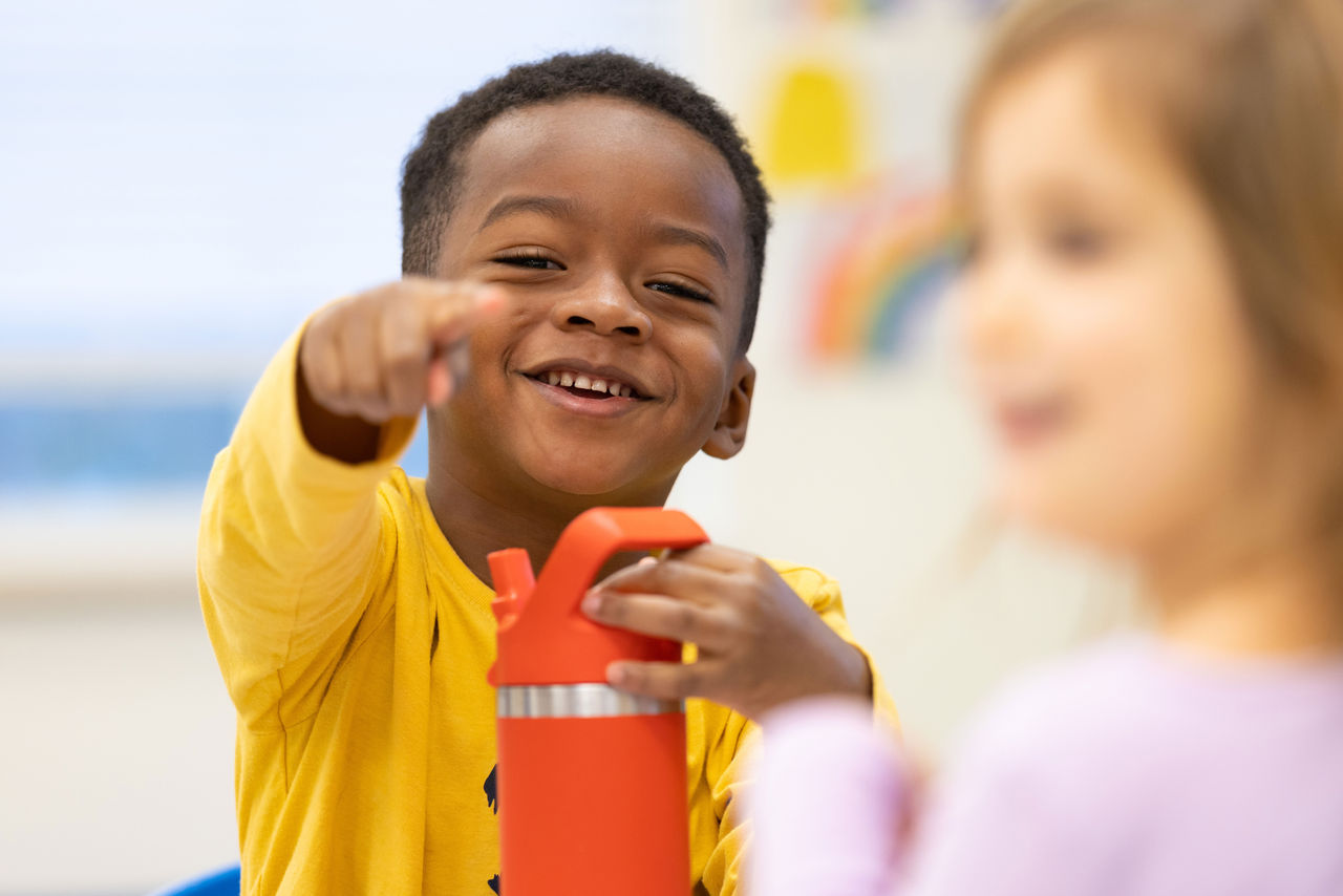 Smiling child with his water bottle excited to start eating lunch