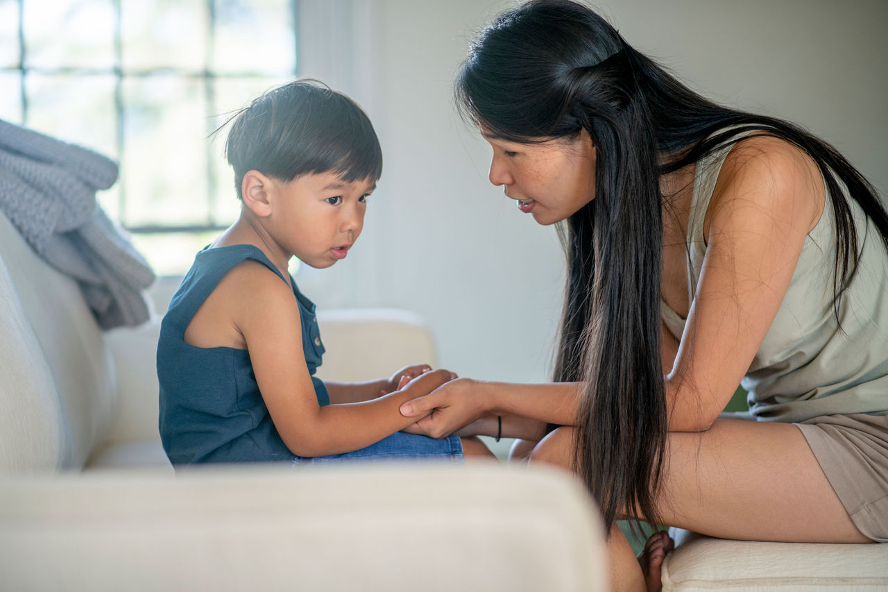 A mother talking to her son while holding his hands