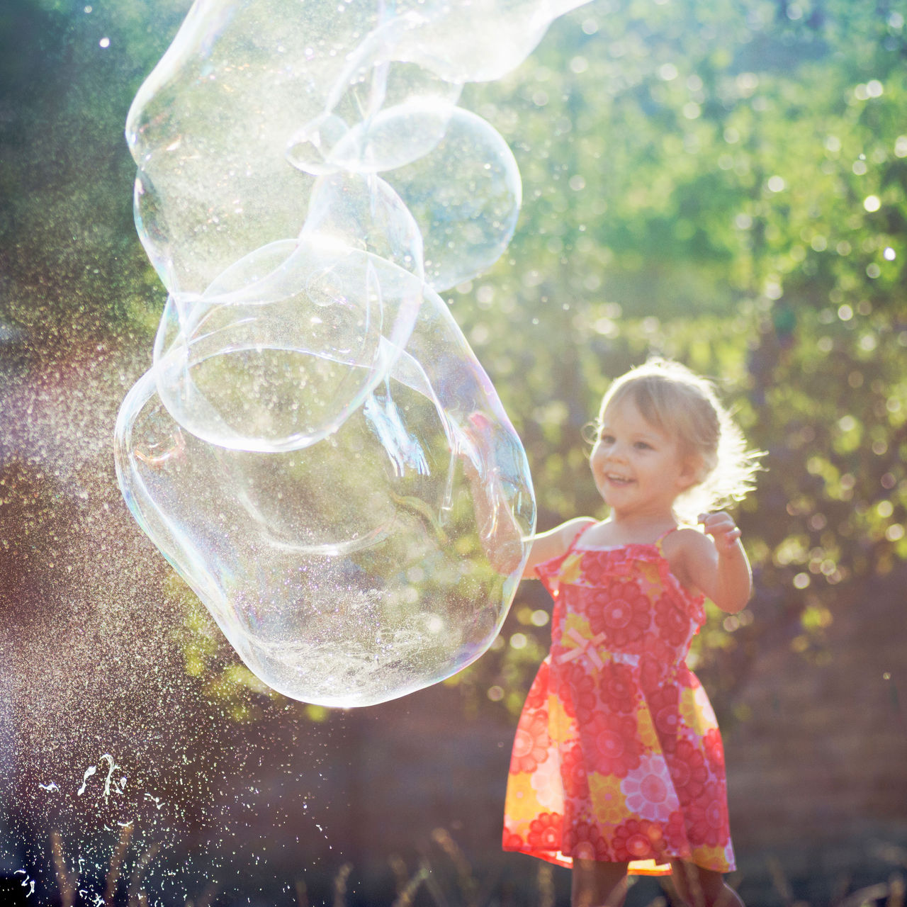 Girl standing in the sun with giant bubbles