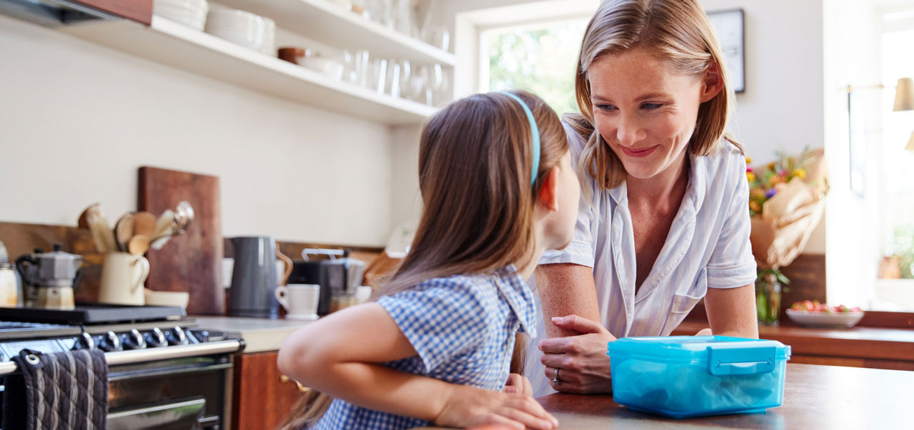 Mother and daughter make school lunch in kitchen