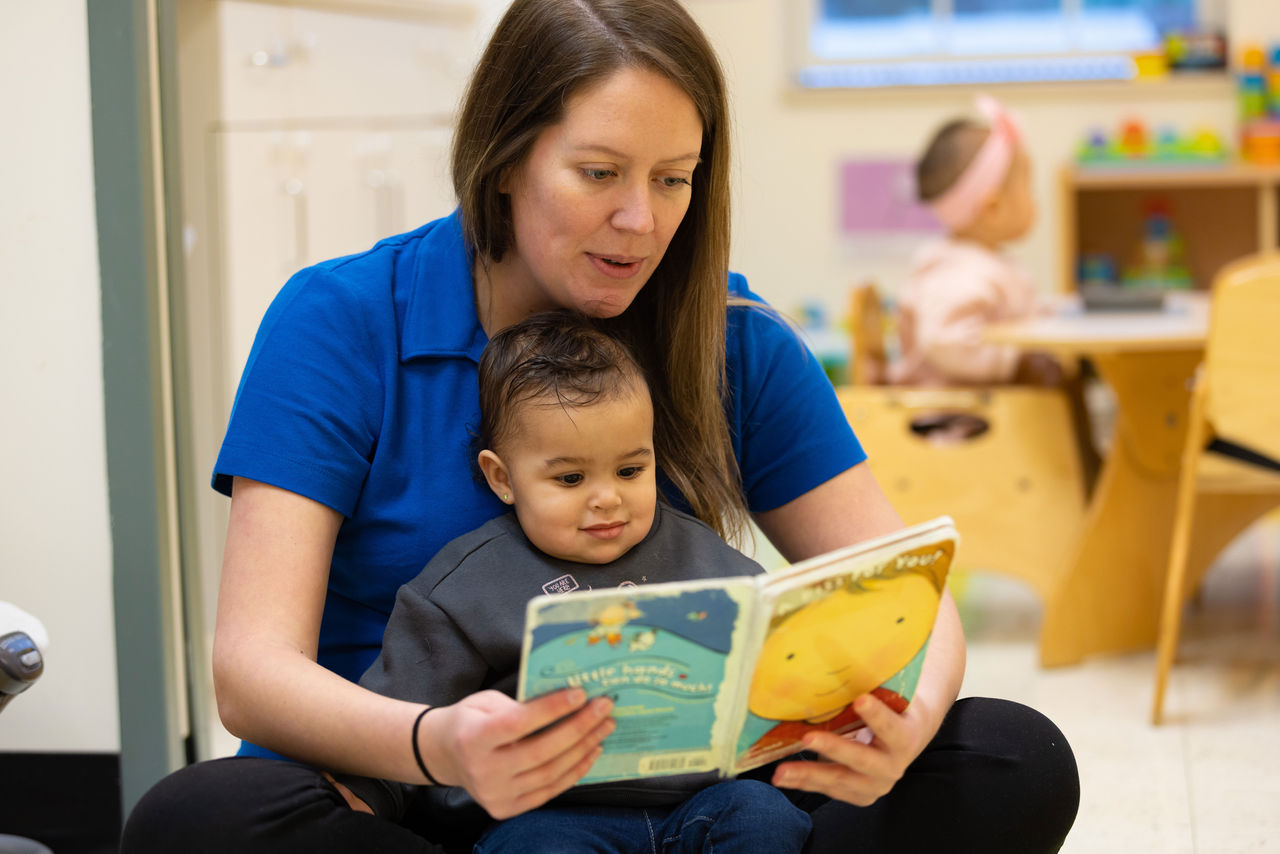 Two women read a book to a preschool age child