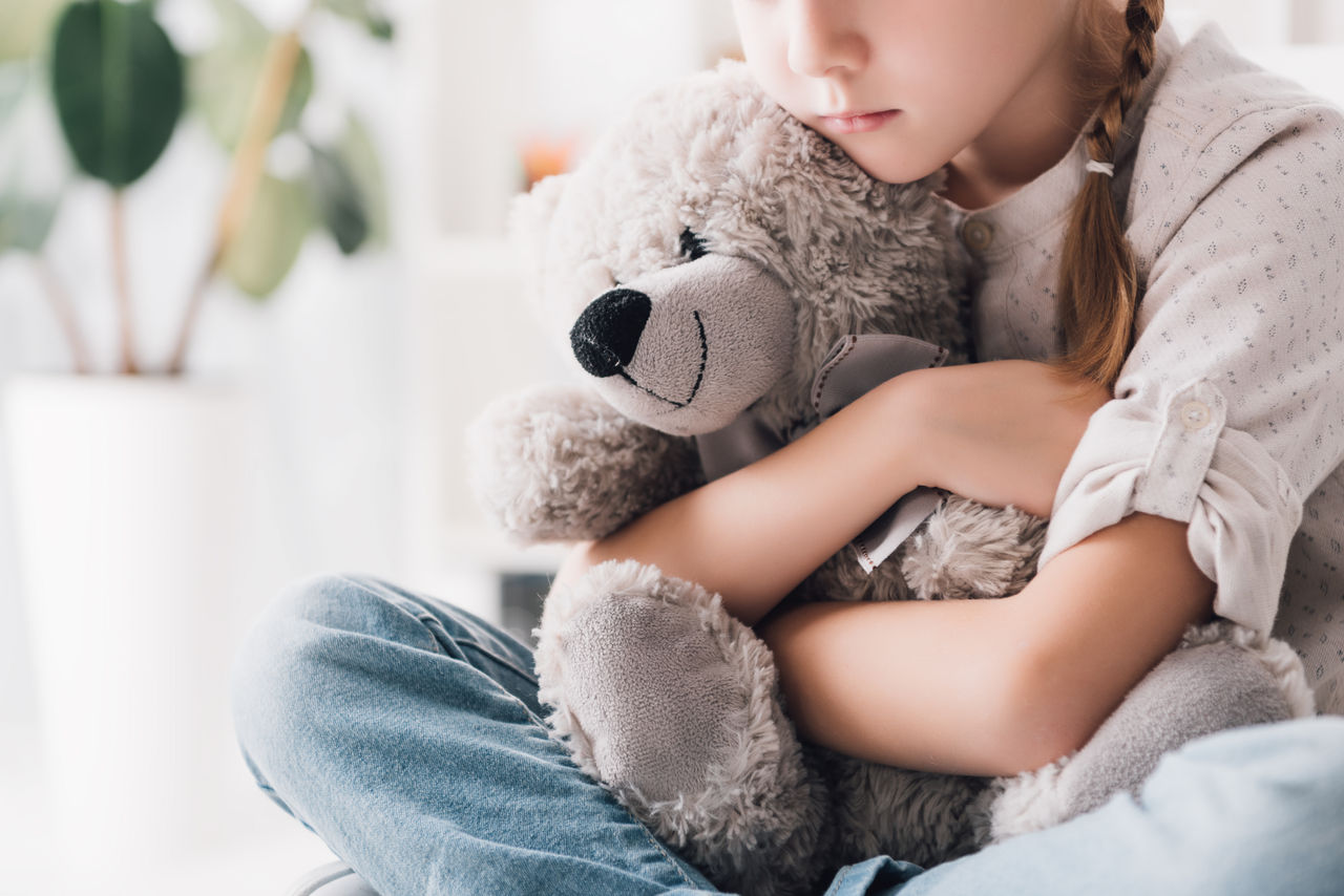 Sad child hugging a teddy bear