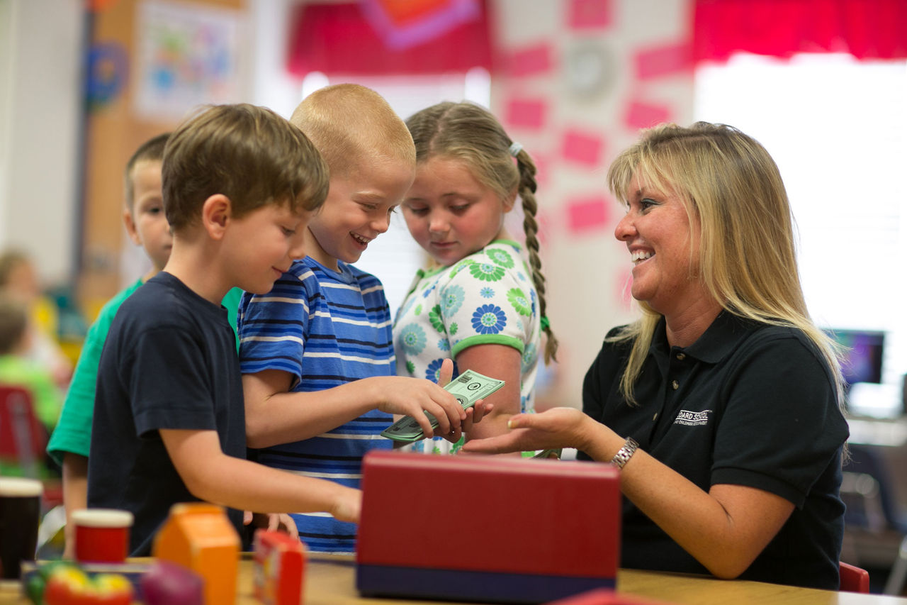 A teacher and children playing with play money