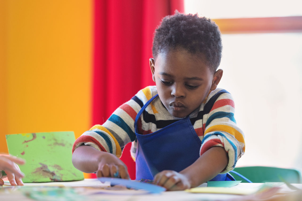 Young boy wearing a smock working on a craft project