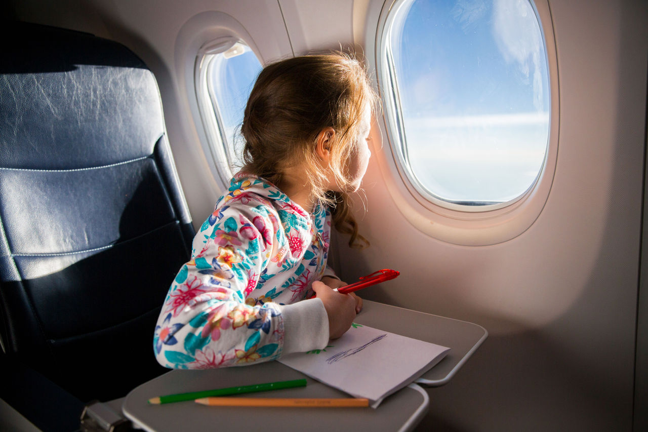 Young child looks out the window of an airplane