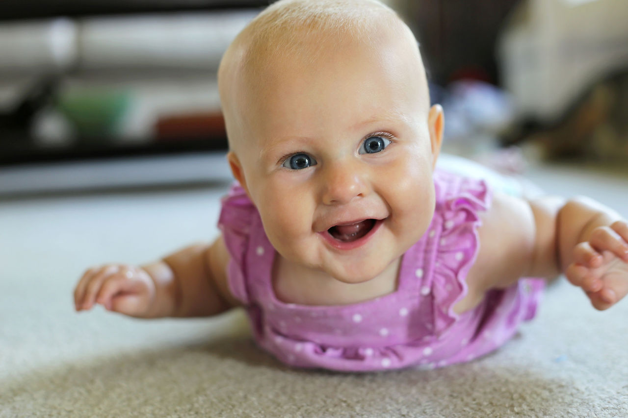 A smiling baby enjoying tummy time