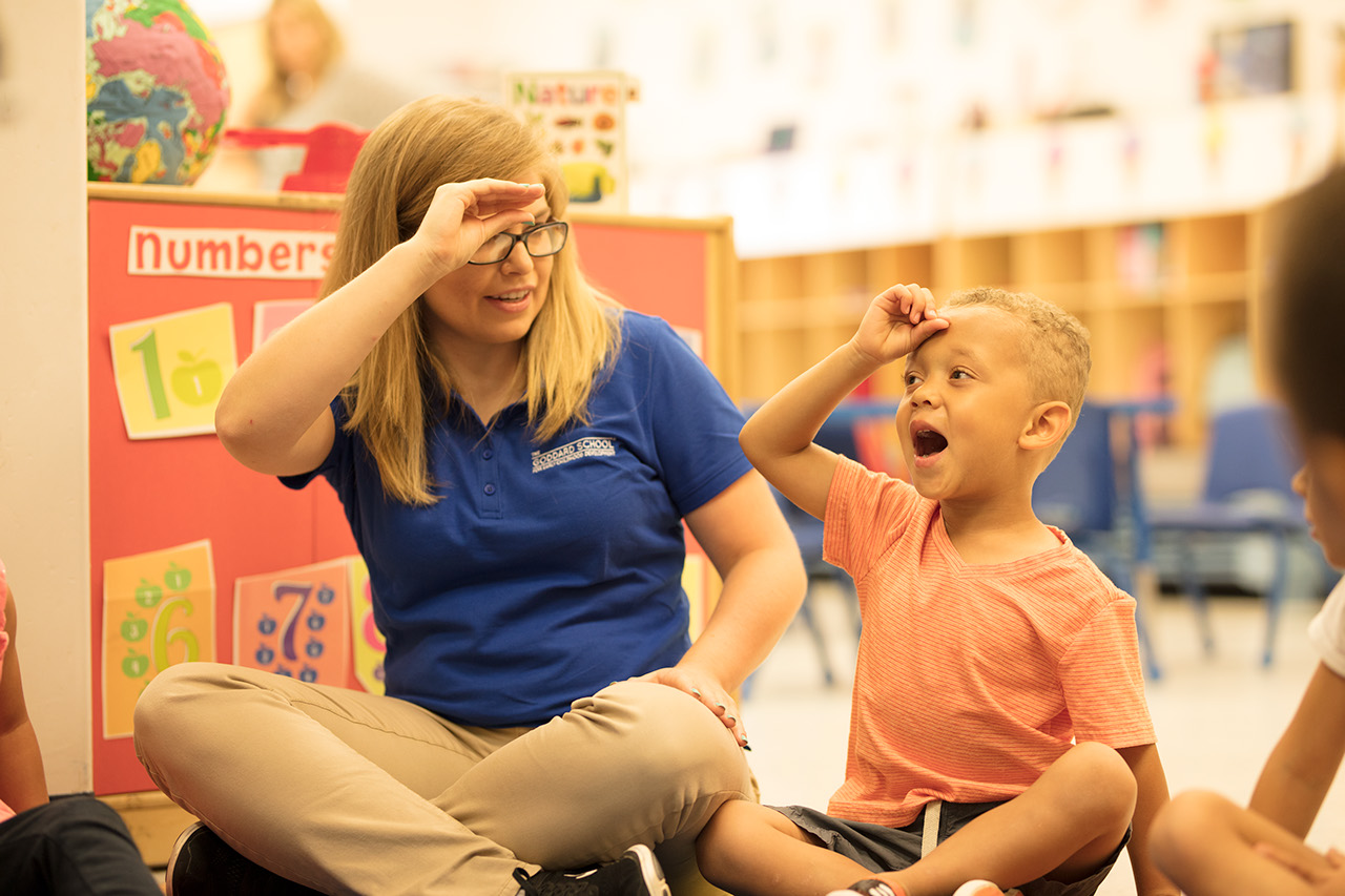 A young boy learns sign language alongside his teacher and classmates.