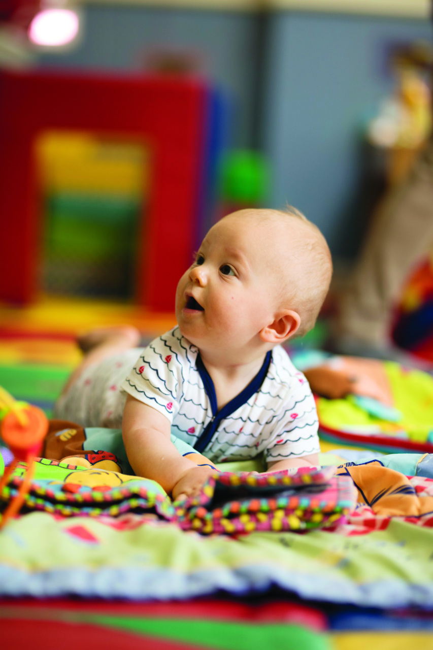 An infant laying on a playset with toys